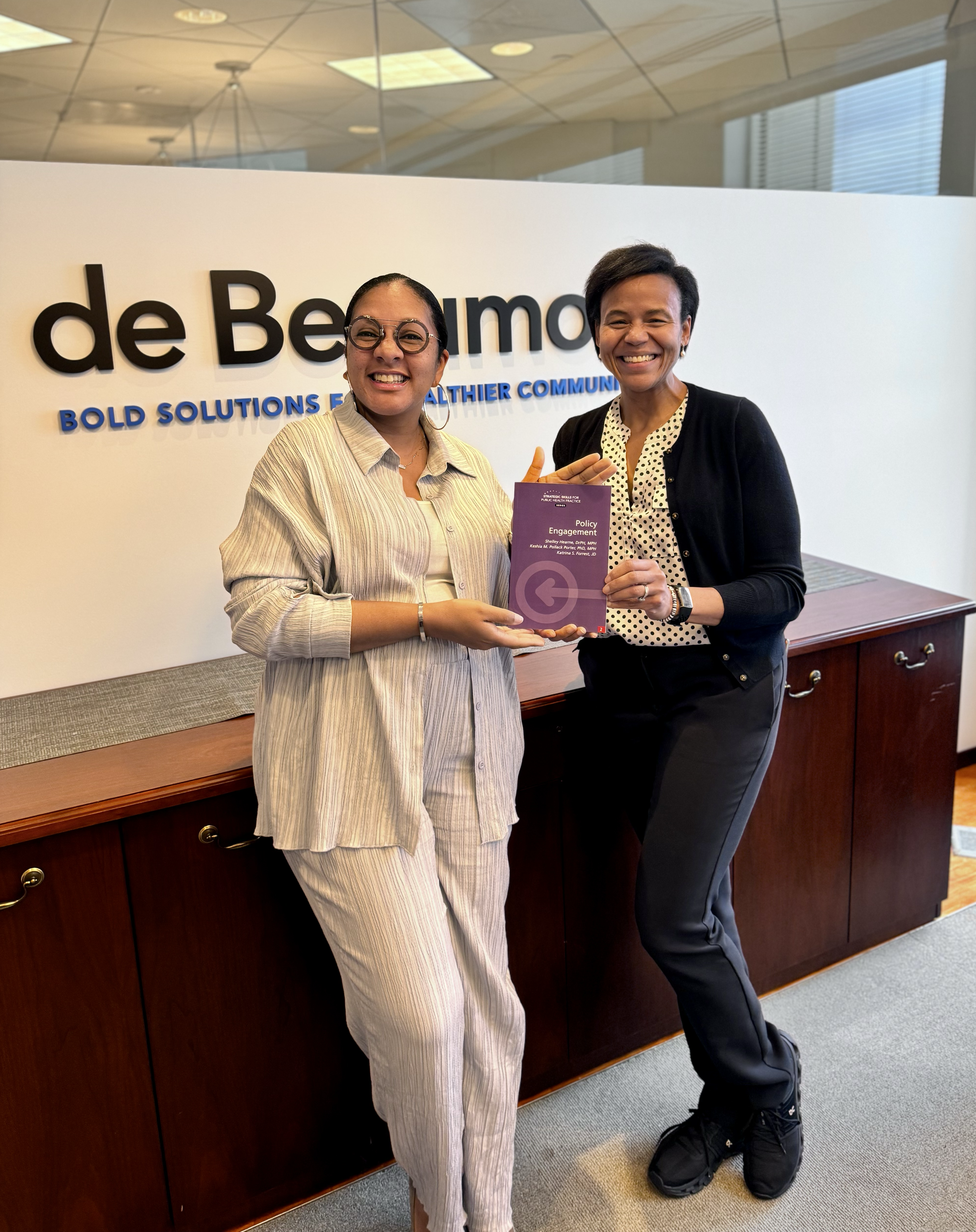 Katrina Forrest and Keshia Pollack Porter pose with a copy of their book, Strategic Skills for Public Health Practice: Policy Engagement.