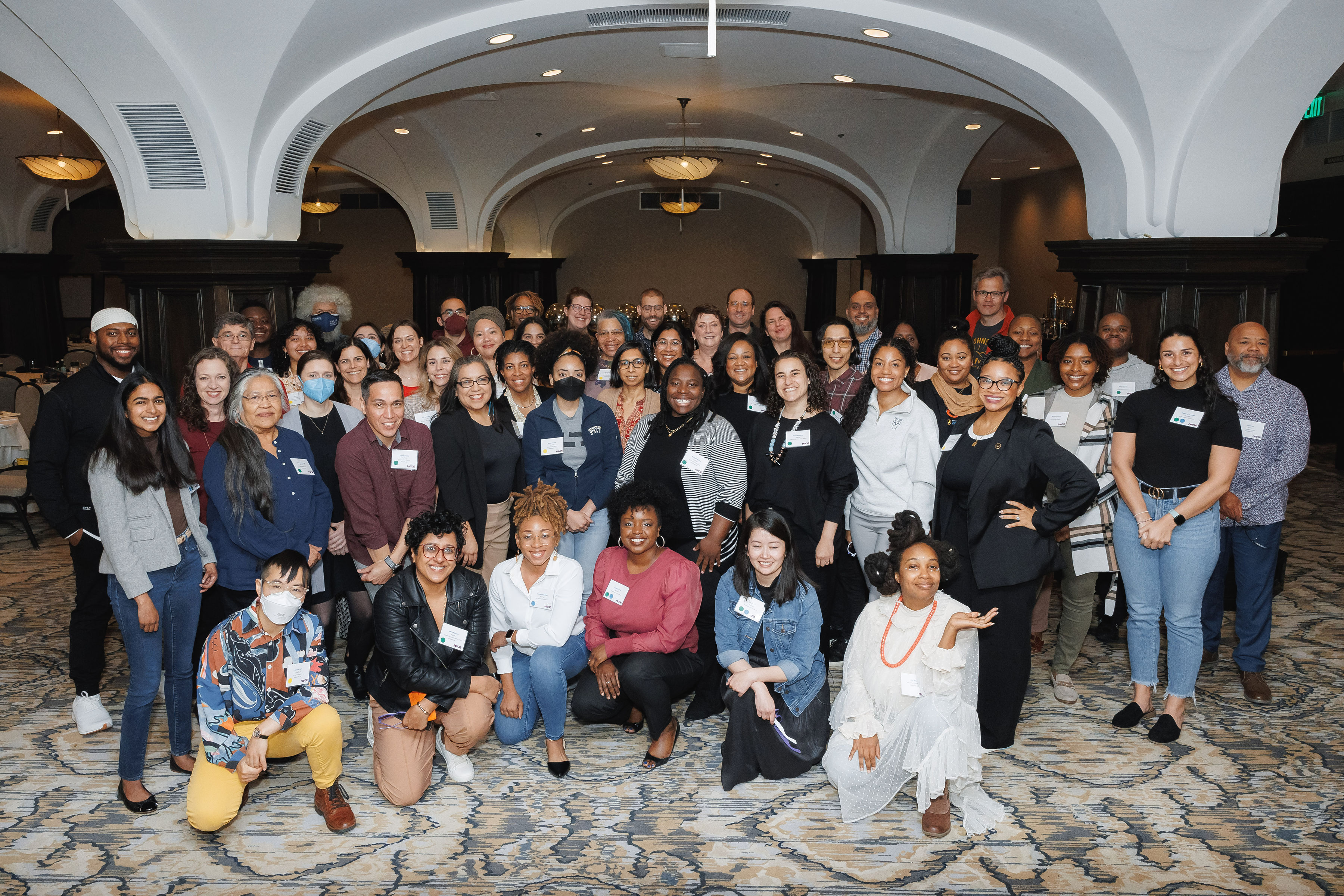 A group of about 50 people who participated in the first MADE for Health Justice 2024 spring convening. People in the first row kneel while people behind them stand.